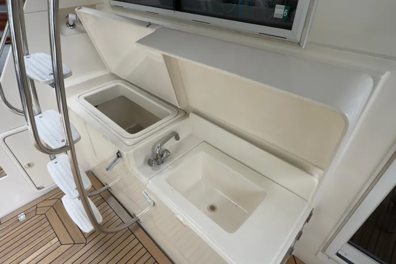 Slide: The Image of 2001 Riviera Twin Cabin Convertible yacht sink and storage area with ladder and teak flooring. - 26