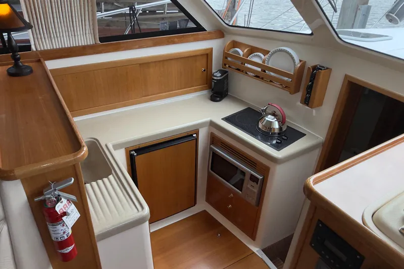 Slide: The Image of 2001 Riviera Twin Cabin Convertible yacht kitchen with stove, microwave, and wooden cabinetry. - 5