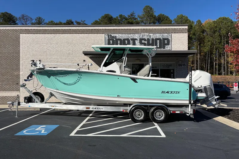 Slide: The Image of 2023 Blackfin 272CC boat on trailer outside a shop, parked in a handicap space. - 0