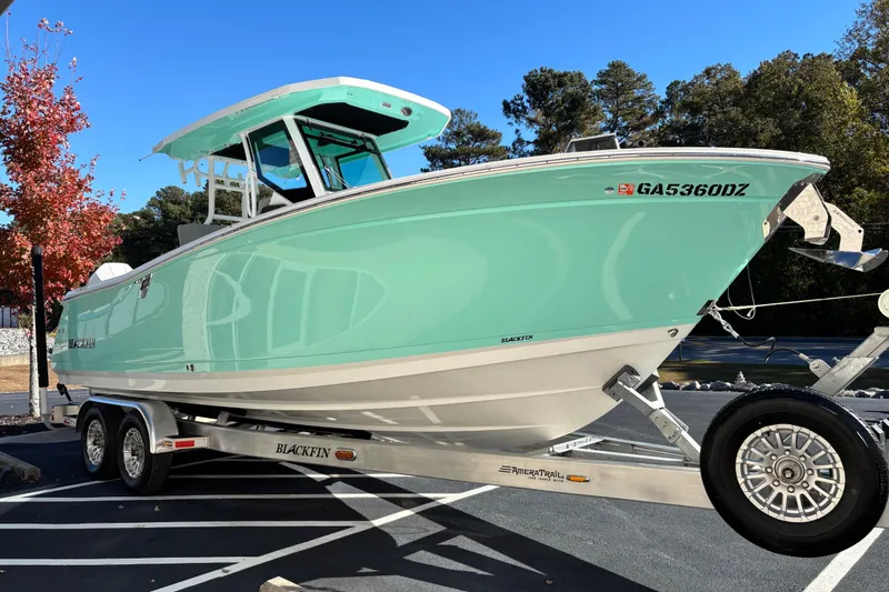 Slide: The Image of 2023 Blackfin 272CC boat on trailer, mint green hull, parked outdoors. - 2