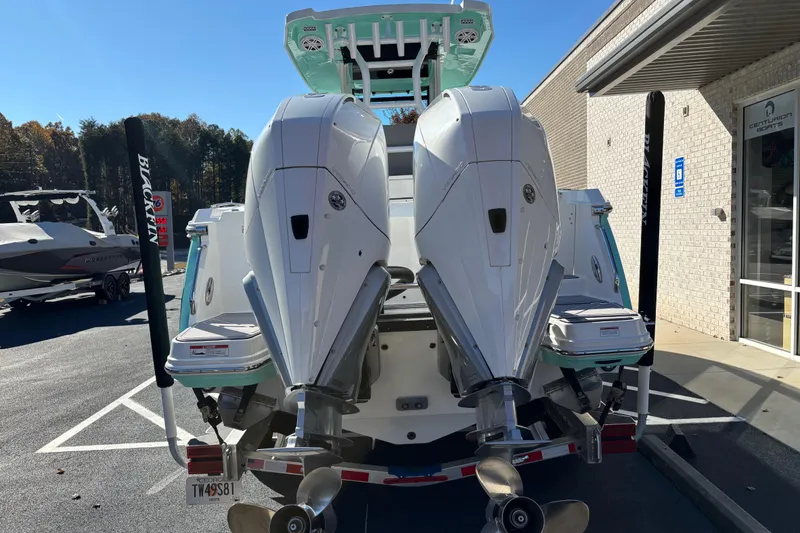 Slide: The Image of 2023 Blackfin 272CC boat with dual outboard engines, parked outside a dealership. - 3