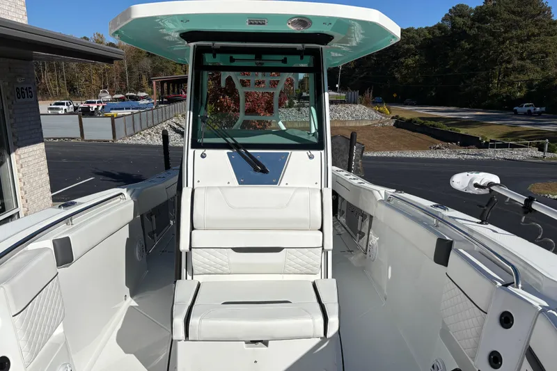 Slide: The Image of 2023 Blackfin 272CC boat interior with seating and helm, parked outdoors. - 7