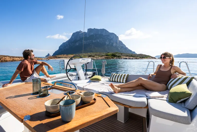 Slide: The Image of Couple relaxing on 2026 Beneteau Oceanis 52 yacht, scenic coastal backdrop. - 2
