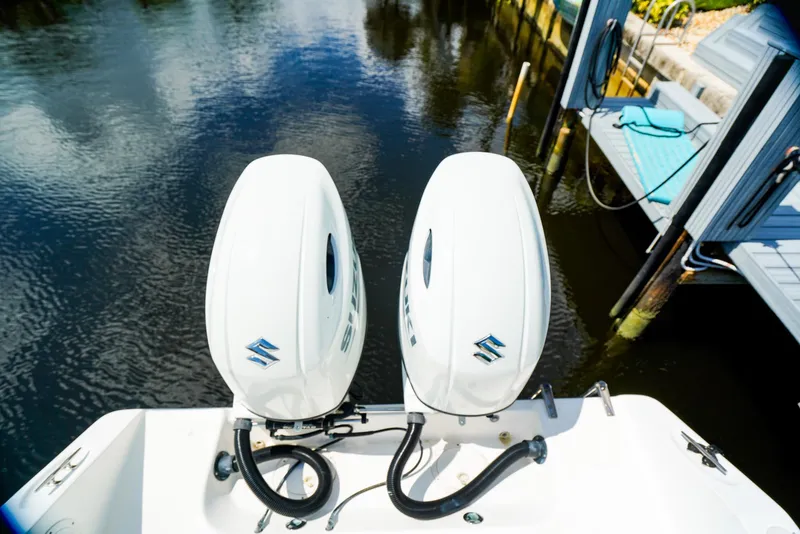 Slide: The Image of Twin Suzuki outboard motors on a 1999 Century 2600 CC boat, docked by the water. - 11