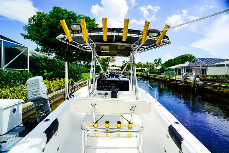 Slide: The Image of Century 2600 CC 1999 boat docked by a canal, featuring a center console and rod holders. - 6