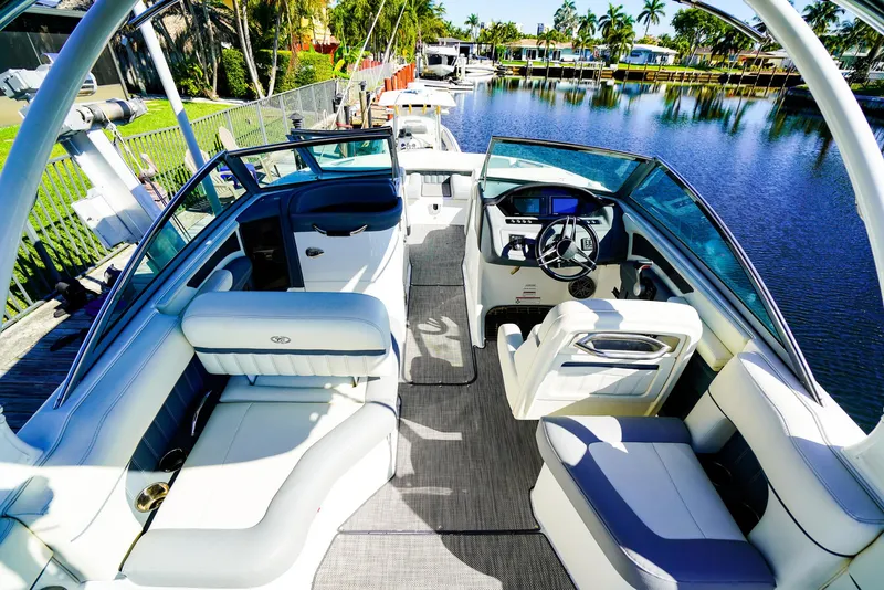 Slide: The Image of 2019 Cobalt 23SC boat interior with luxurious seating and modern dashboard by a scenic waterfront. - 12