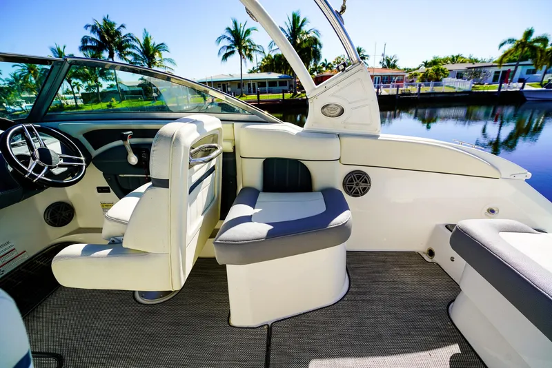 Slide: The Image of 2019 Cobalt 23SC boat interior with plush seating, steering wheel, and scenic waterfront view. - 7