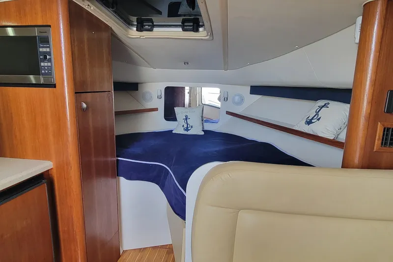 Slide: The Image of 2006 Tiara Yachts 2900 Open Classic cabin interior with bed, wood cabinetry, and nautical decor. - 14