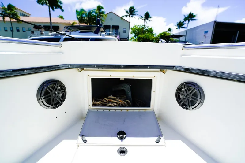 Slide: The Image of 2001 Whitewater 28 Open boat interior with storage compartment and speakers, docked under clear skies. - 19