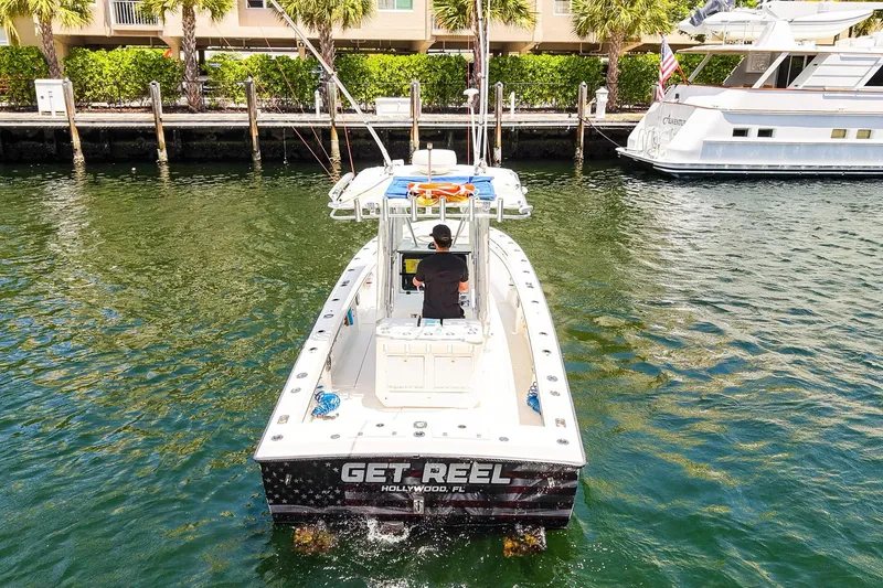 Slide: The Image of 2001 Whitewater 28 Open boat cruising in a marina, featuring "Get Reel" on the stern. - 26