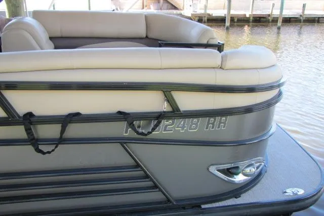 Slide: The Image of 2018 Regency 220 DL3 pontoon boat with beige seating, docked by the water. - 14