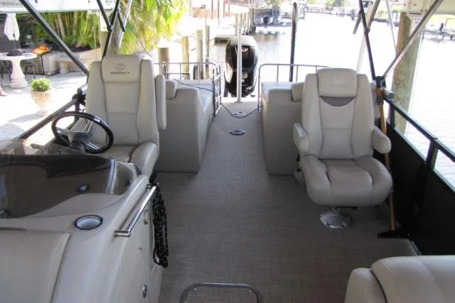 Slide: The Image of 2018 Regency 220 DL3 pontoon boat interior with plush seating and steering console. - 5