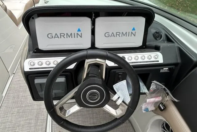 Slide: The Image of 2023 Crownline 260 SS boat dashboard with dual Garmin displays and steering wheel. - 3