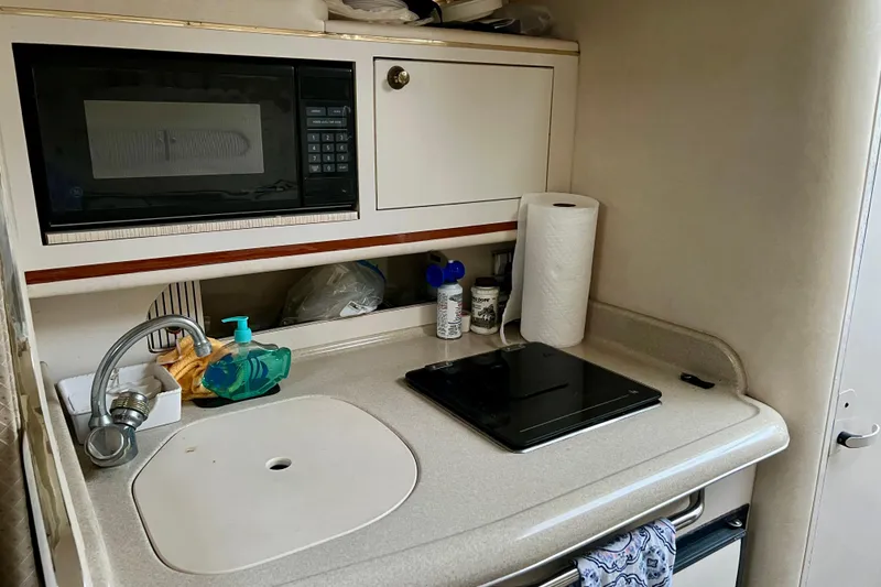 Slide: The Image of Compact kitchen area in a 2000 Sea Ray 270 Sundancer boat, featuring a microwave and sink. - 15