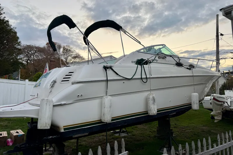 Slide: The Image of 2000 Sea Ray 270 Sundancer boat on land, with overcast sky background. - 5