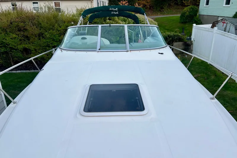 Slide: The Image of 2000 Sea Ray 270 Sundancer boat deck with windshield and hatch, docked in a residential area. - 6