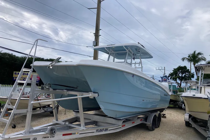 Slide: The Image of 2021 Twin Vee 280 GFX CC boat on trailer, displayed outdoors under cloudy sky. - 1