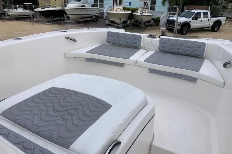 Slide: The Image of 2021 Twin Vee 280 GFX CC boat with cushioned seating, parked near other boats and a truck. - 10