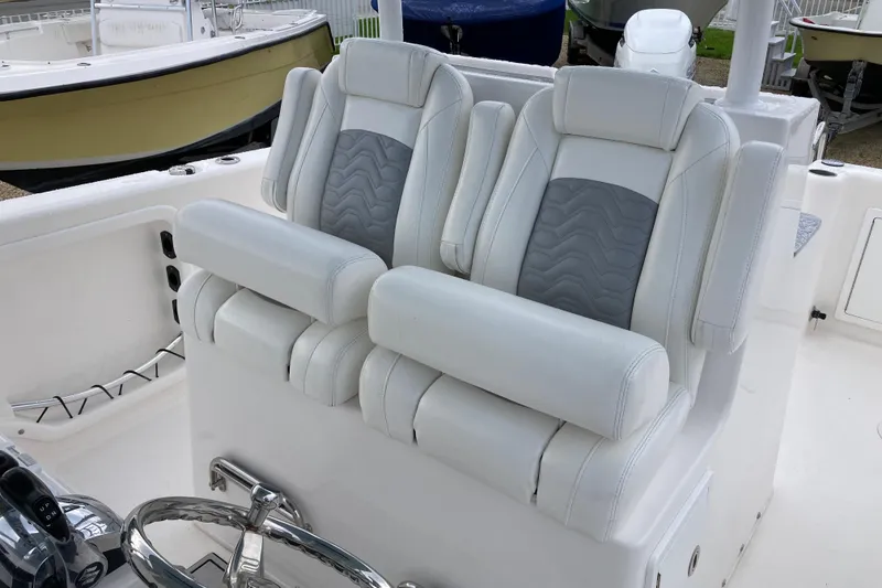 Slide: The Image of Twin Vee 280 GFX CC 2021 boat seats, white and gray upholstery, dual helm chairs. - 13
