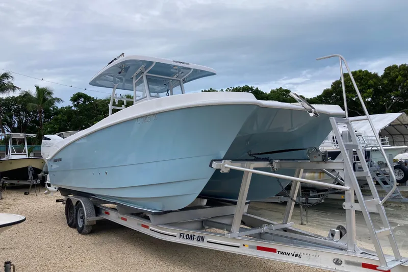 Slide: The Image of 2021 Twin Vee 280 GFX CC boat on trailer, light blue hull, parked outdoors. - 2