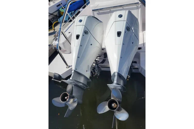 Slide: The Image of Twin outboard motors on a 2023 Axopar 28 Cabin boat, docked in water. - 10