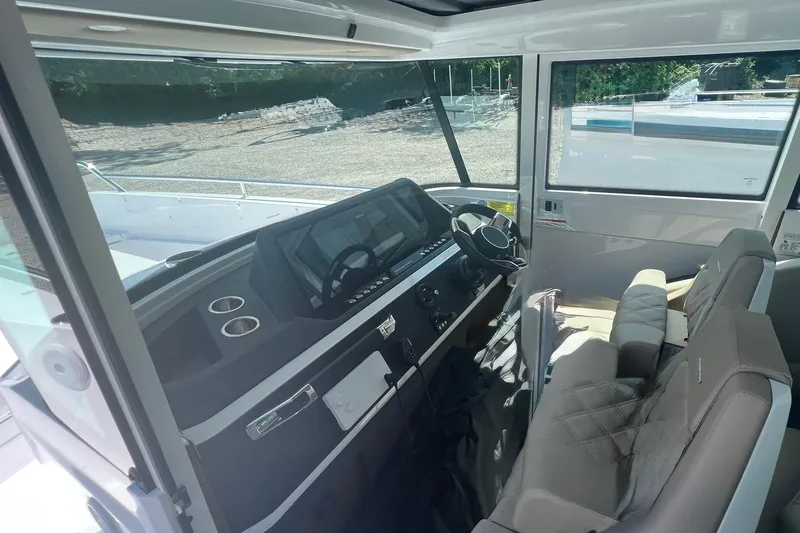 Slide: The Image of 2023 Axopar 28 Cabin Wet Bar interior with modern dashboard and comfortable seating. - 11