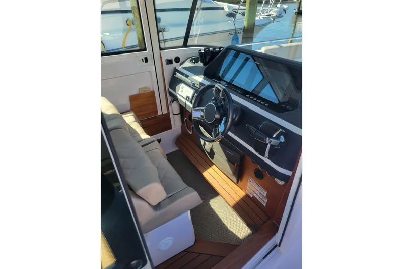 Slide: The Image of 2023 Axopar 28 Cabin interior with modern steering console and seating. - 12