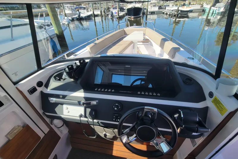 Slide: The Image of 2023 Axopar 28 Cabin boat interior with modern dashboard and steering wheel. - 13