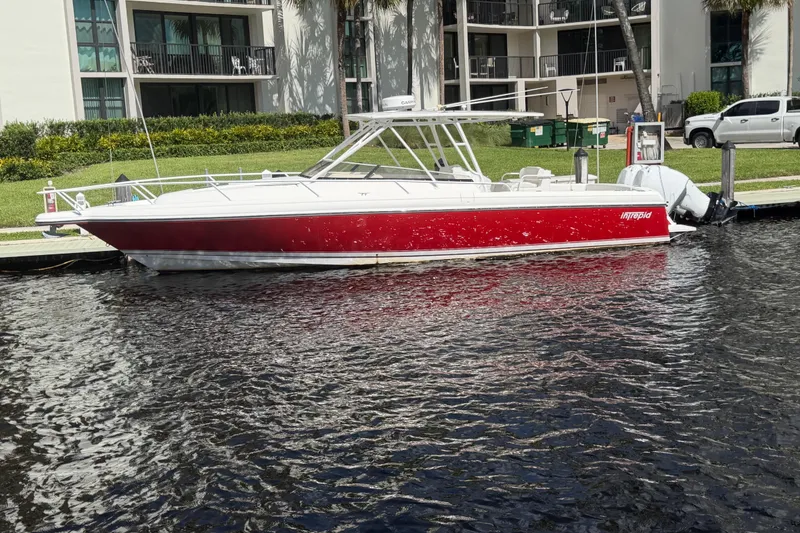 The Image of 2008 Intrepid 350 Center Console boat docked, featuring a sleek red and white design. - 0