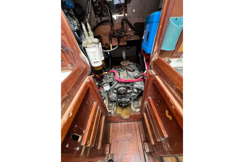 Slide: The Image of 1976 Westsail 32 interior with wooden cabinetry, red cushions, and nautical decor. - 56