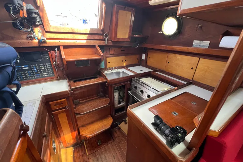 Slide: The Image of 1976 Westsail 32 sailboat interior with red seating, wooden cabinetry, and nautical decor. - 57