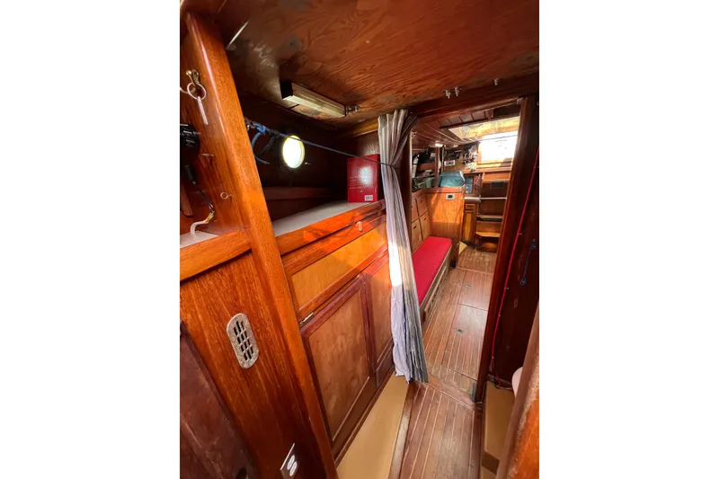 Slide: The Image of 1976 Westsail 32 interior with wooden cabinetry, compact kitchen, and cozy sleeping area. - 58
