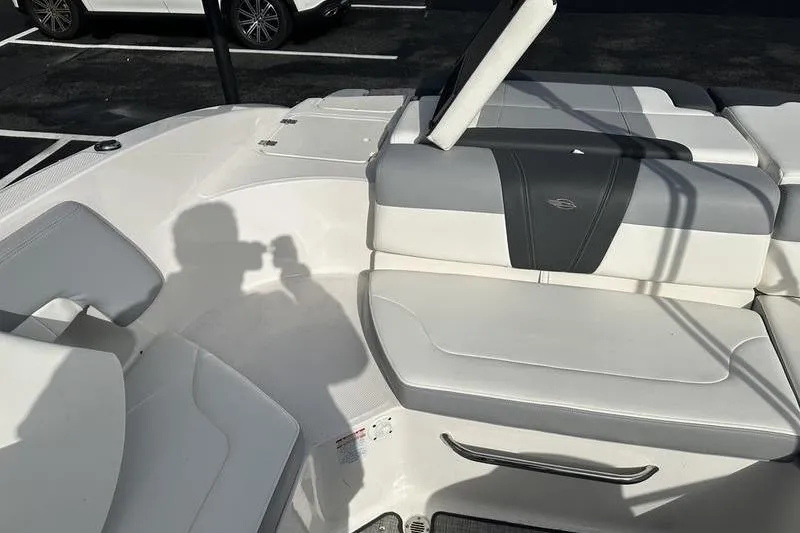Slide: The Image of 2022 Chaparral 23 SSi boat interior with white and gray seating in parking lot. - 16