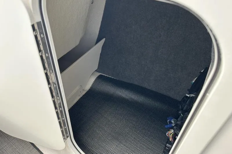 Slide: The Image of Interior storage compartment of 2022 Chaparral 23 SSi boat, featuring carpeted flooring. - 29