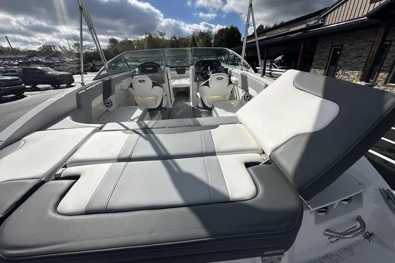 Slide: The Image of 2022 Chaparral 23 SSi boat interior with seating and sun pad under cloudy sky. - 8