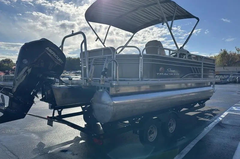 Slide: The Image of 2023 Sun Tracker Party Barge 20 DLX pontoon boat on trailer, under a clear sky. - 11