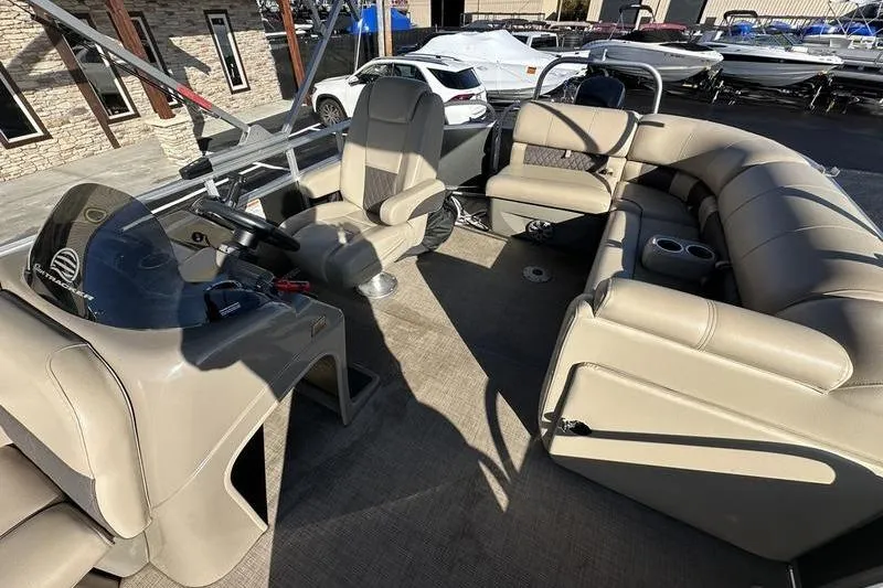 Slide: The Image of 2023 Sun Tracker Party Barge 20 DLX interior with beige seating and steering console. - 14