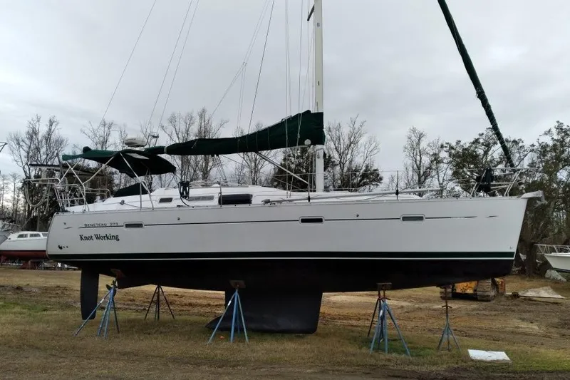 Slide: The Image of 2005 Beneteau Oceanis 373 sailboat on stands, named "Knot Working," in a boatyard. - 62