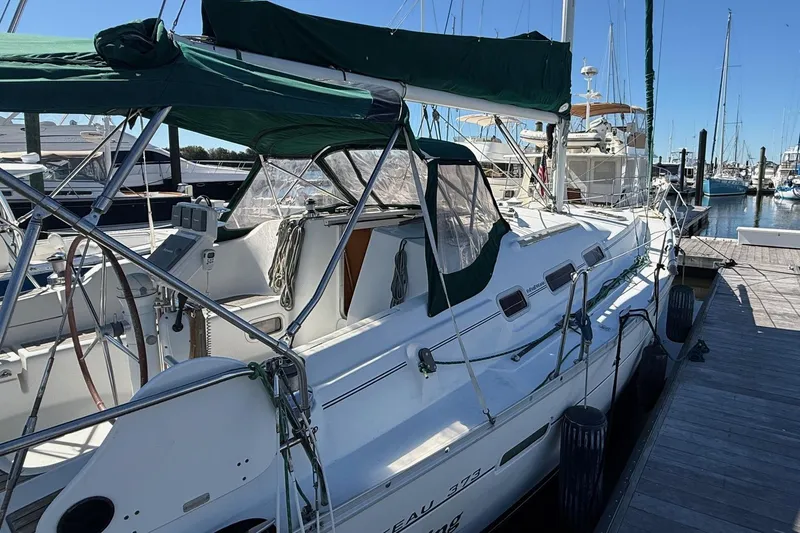 Slide: The Image of 2005 Beneteau Oceanis 373 sailboat docked at marina, featuring green canopy. - 7