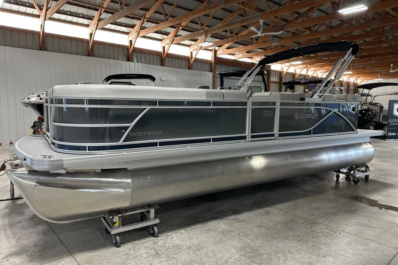 Slide: The Image of 2026 Godfrey Sweetwater 2286 C pontoon boat in a spacious indoor storage facility. - 2