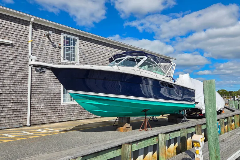 The Image of 2004 Tiara 29 Coronet Harbor Edition boat on display near a wooden building. - 1