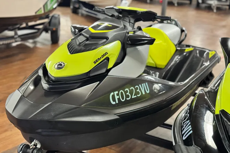 Slide: The Image of 2021 Sea-Doo GTR 230 jet ski in showroom, lime green and black design. - 2