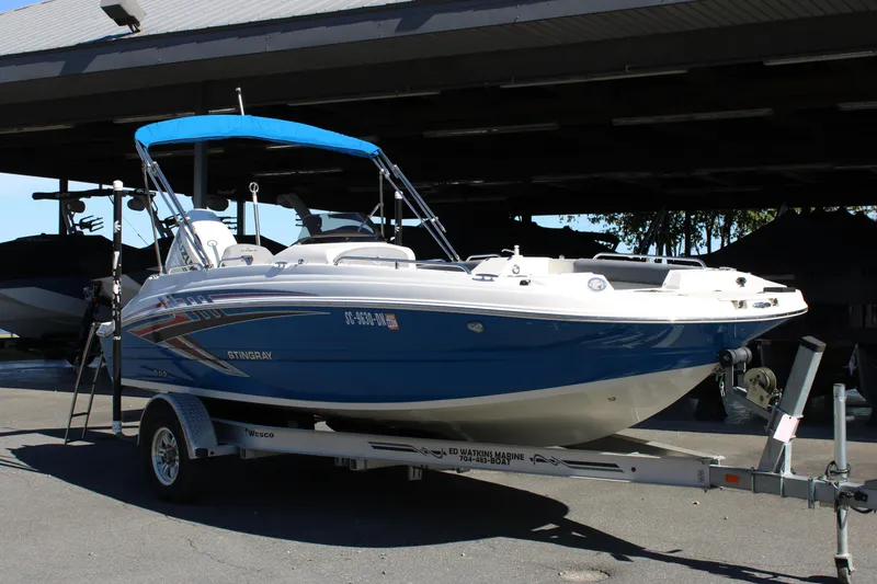 Slide: The Image of 2020 Stingray 192SC boat on trailer with blue canopy, parked outdoors. - 18