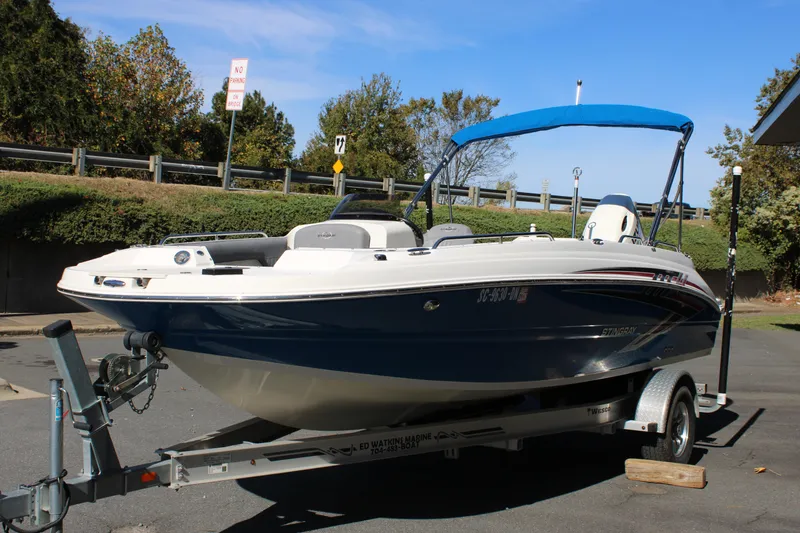 Slide: The Image of 2020 Stingray 192SC boat on trailer with blue canopy, parked outdoors. - 25