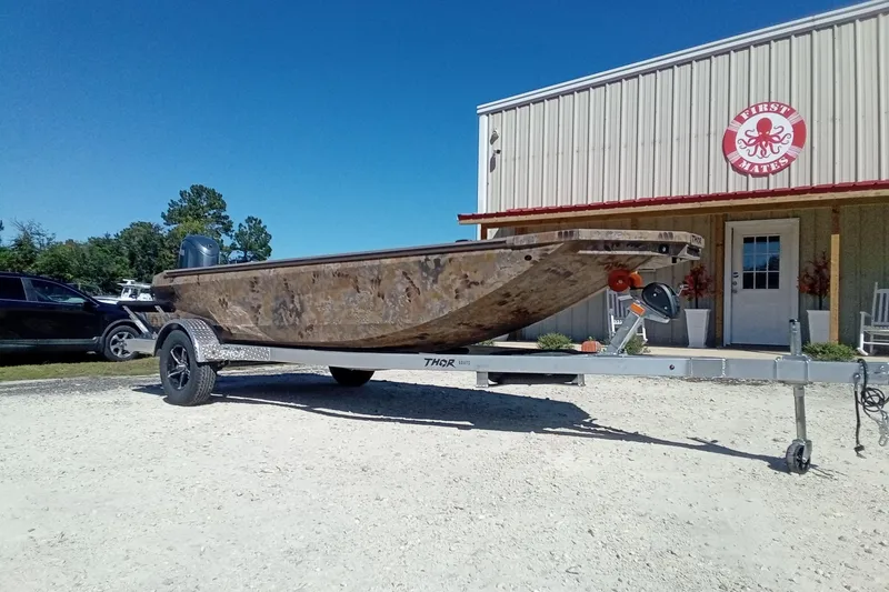Slide: The Image of 2026 Thor 1754 Fish Hammer boat on trailer outside a building under clear blue sky. - 3