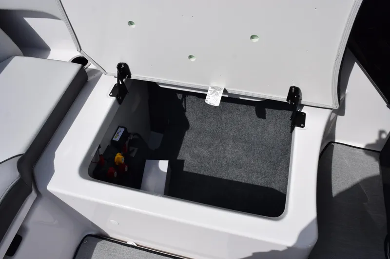 Slide: The Image of Open storage compartment in 2026 Yamaha AR250 boat, featuring carpeted interior and secure hinges. - 21