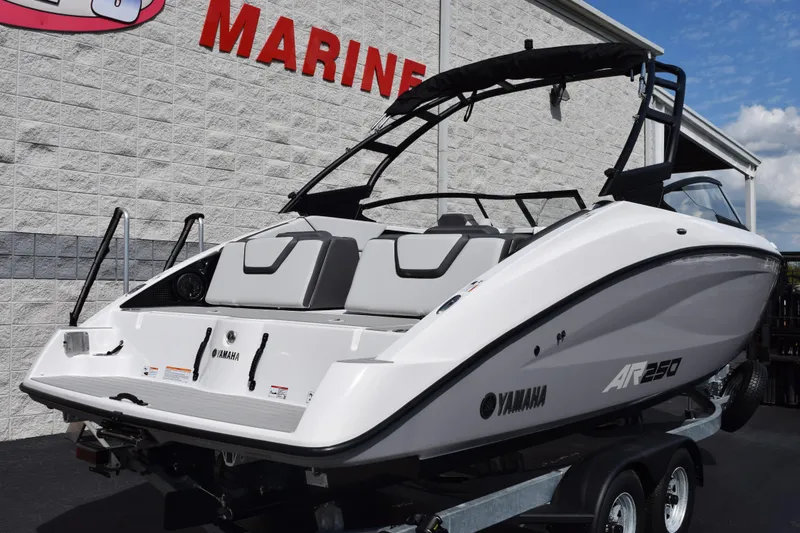 Slide: The Image of 2026 Yamaha AR250 boat on trailer, parked near a marine store. - 4