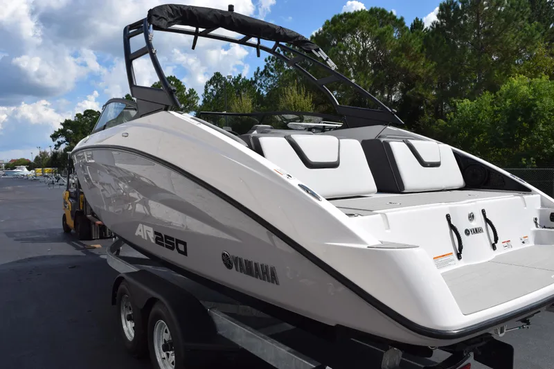Slide: The Image of 2026 Yamaha Boats AR250 on trailer, sleek design, parked outdoors with trees in background. - 6