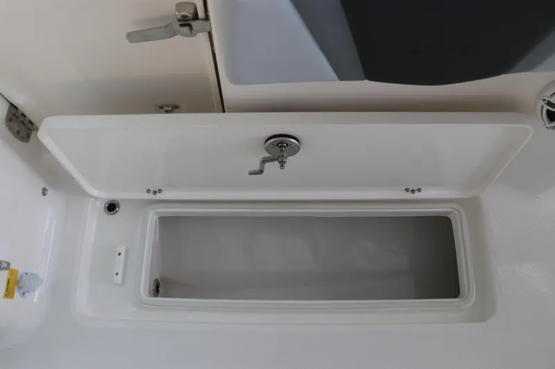 Slide: The Image of 2026 Robalo R250 Center Console storage compartment with open lid and secure latch. - 18