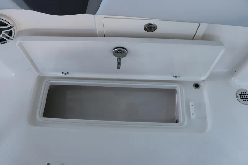 Slide: The Image of 2026 Robalo R250 Center Console storage compartment with open lid and secure lock. - 20